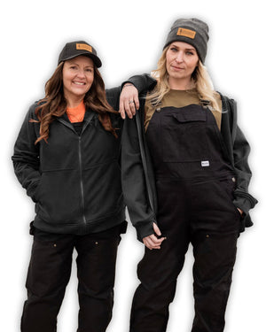 Two people wearing black jackets and hats on a white background